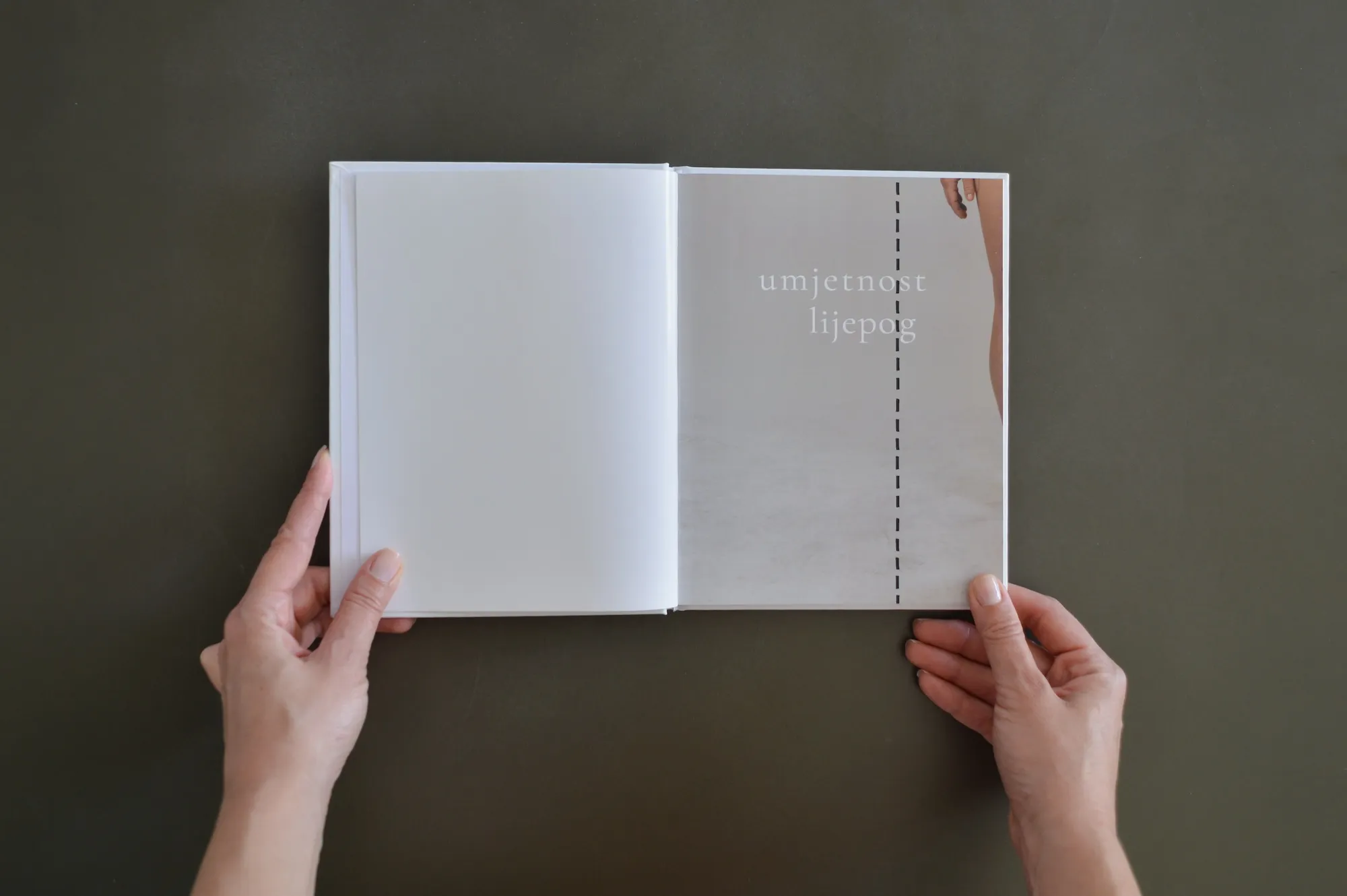 Open book spread showing the title "umjetnost lijepog" printed over a photograph, with a dashed vertical line emphasizing "umjetno lijepo".