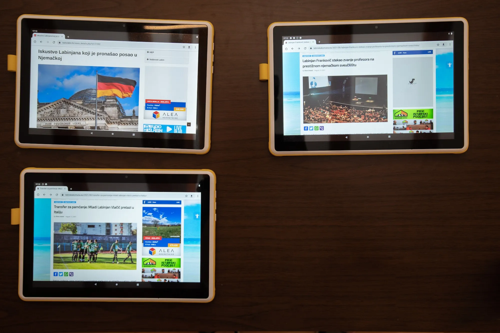 Overhead view of three tablets on a table, each displaying a local news article about Labin.