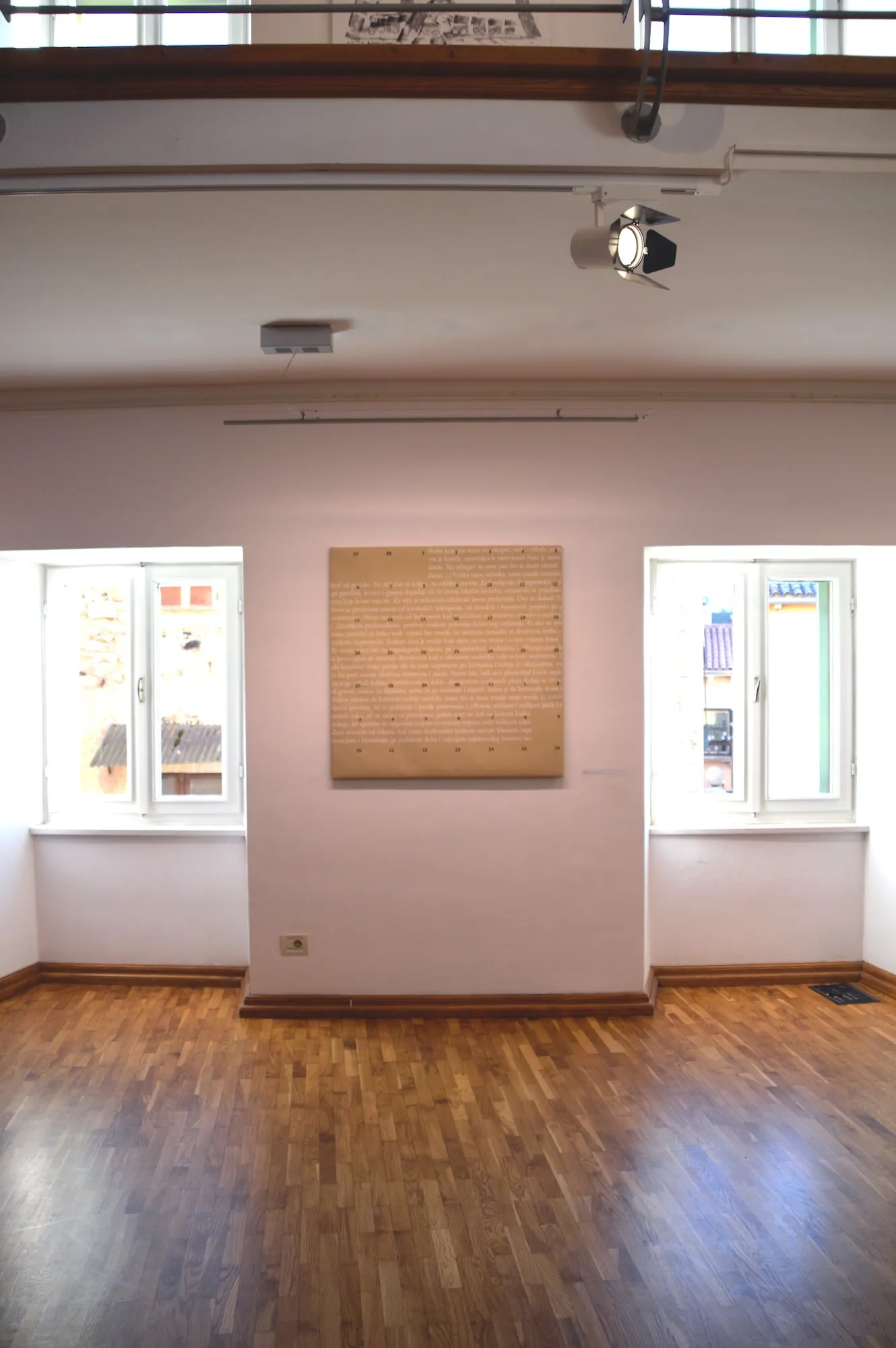 Installation view of the square canvas print hung on a gallery wall between two windows.
