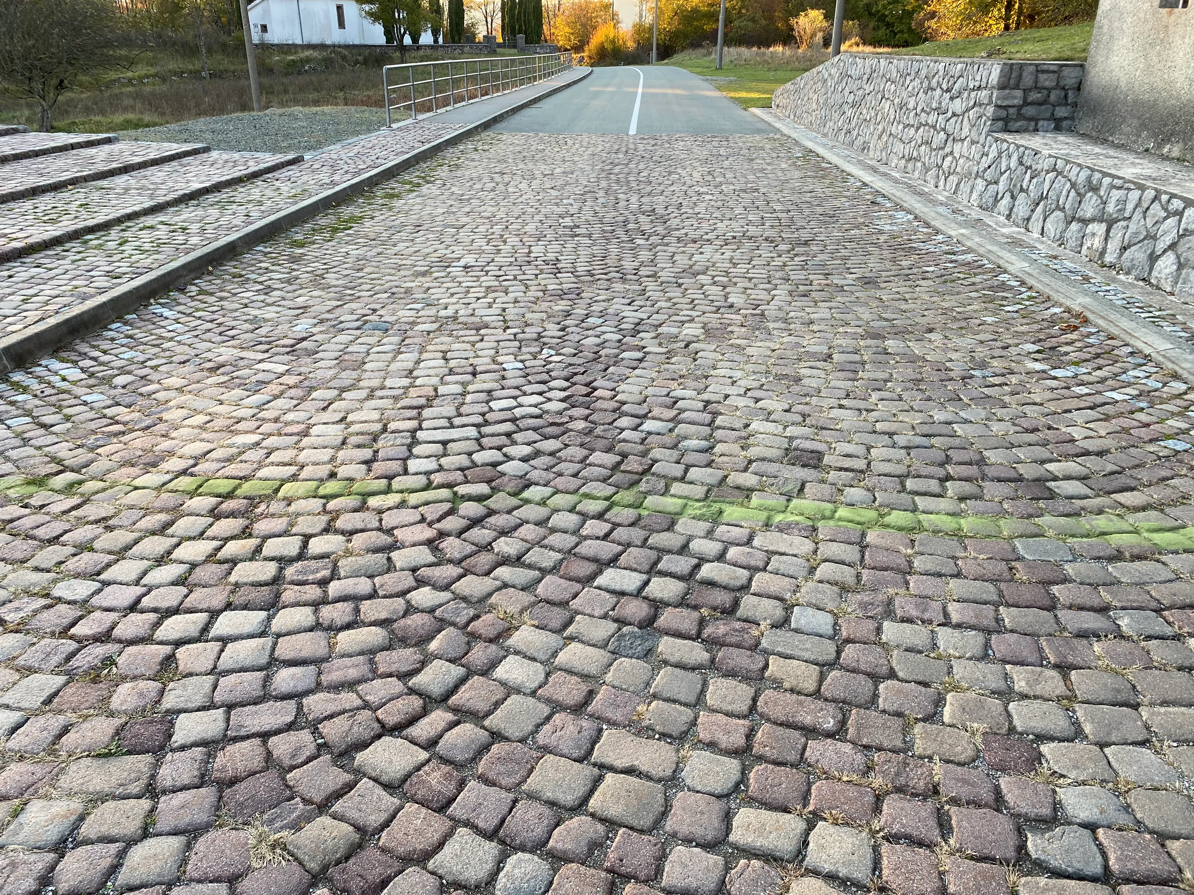 A faint green line of ground linden-leaf powder traced along a cobblestone road in the village of Lipa.