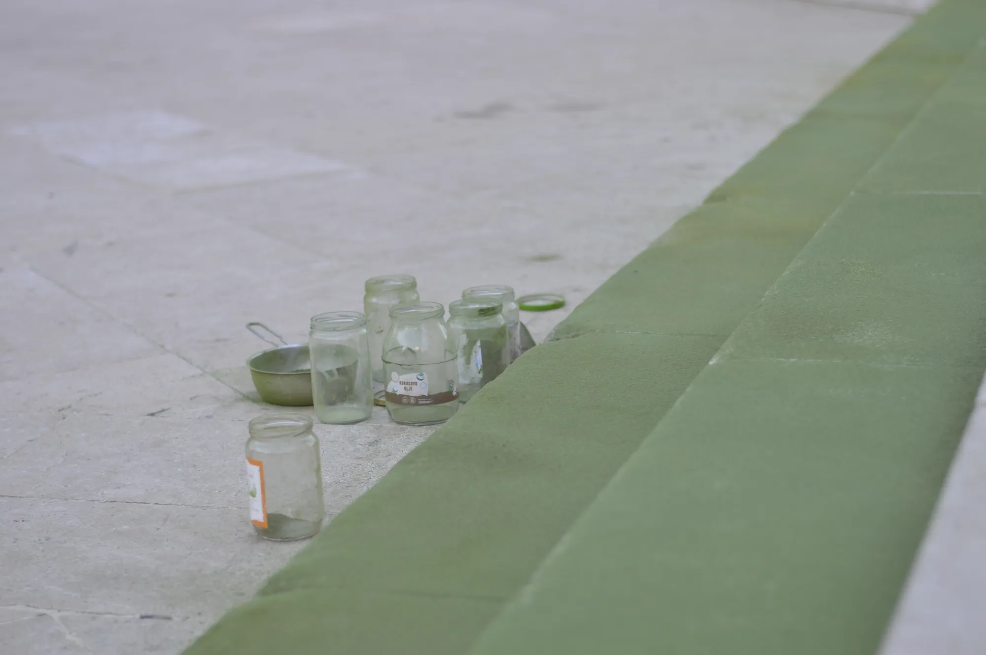 Close-up of the green powder line on the pavement, showing footprints left within it.