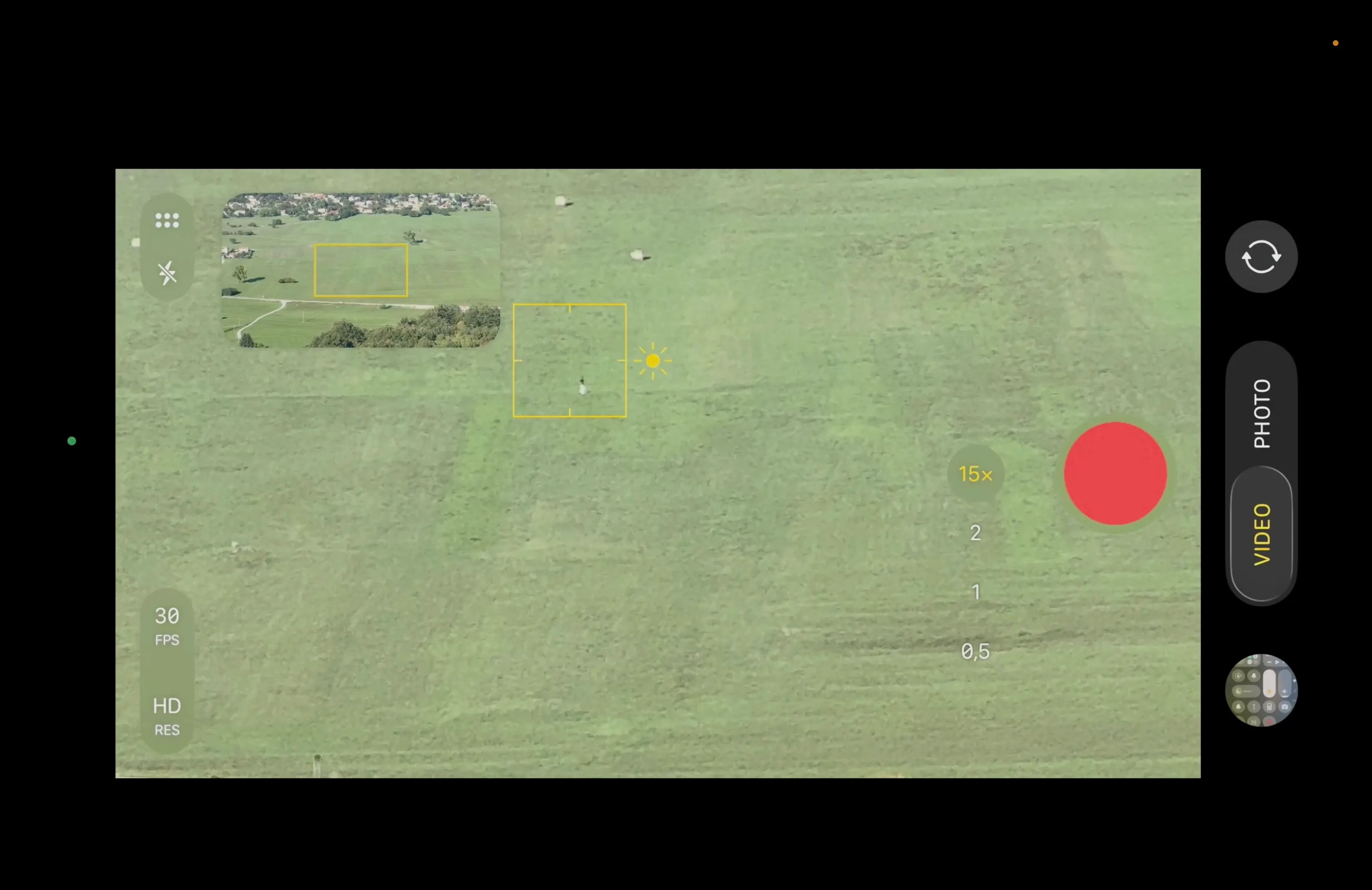 A screen-recorded phone camera interface at 15× zoom, showing a magnified patch of Grobnik Field with a lone figure inside the focus box and a village visible in the overview inset.