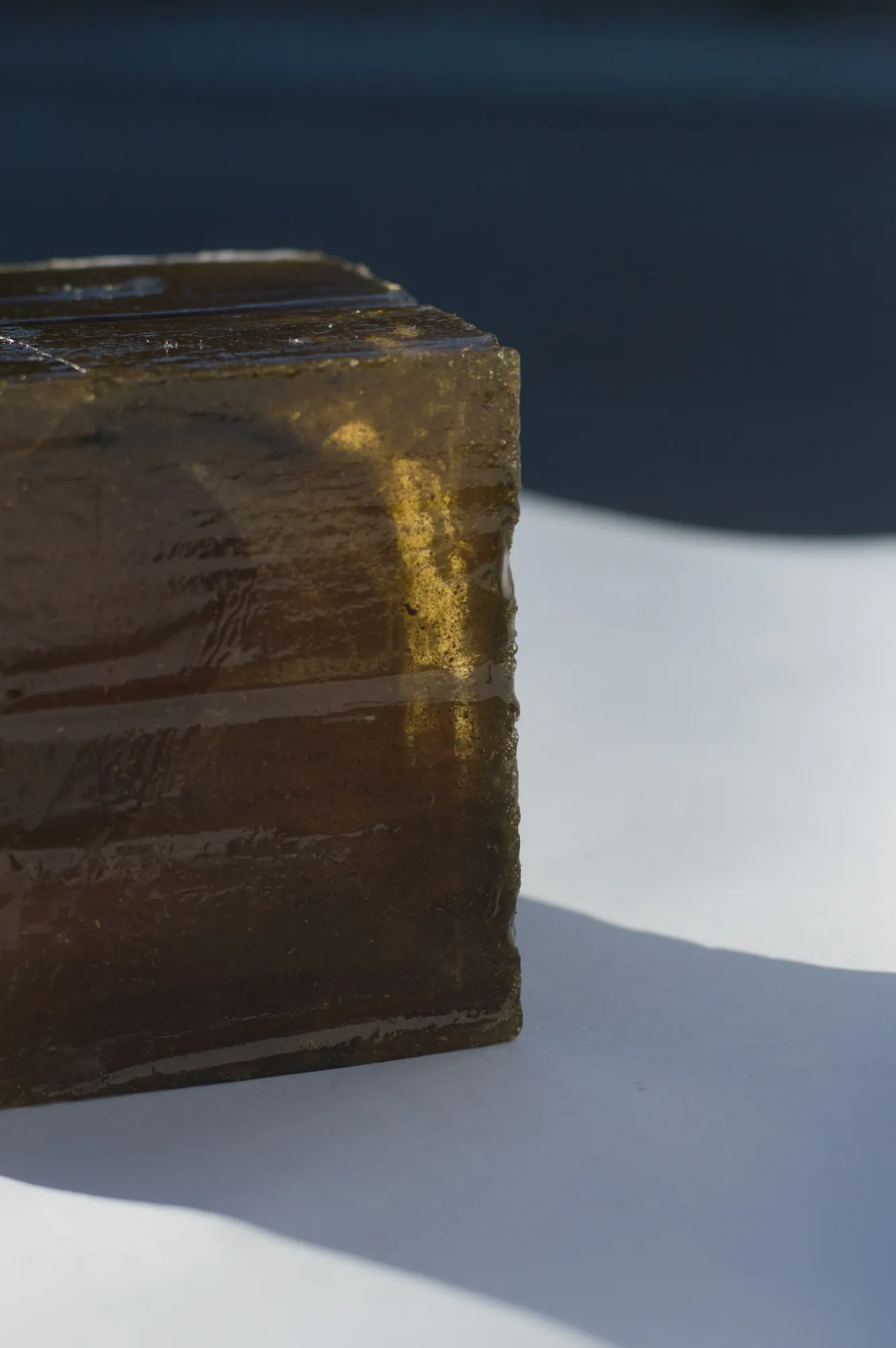 Close-up of a corner of the amber isomalt cube, showing its glassy, textured surface.