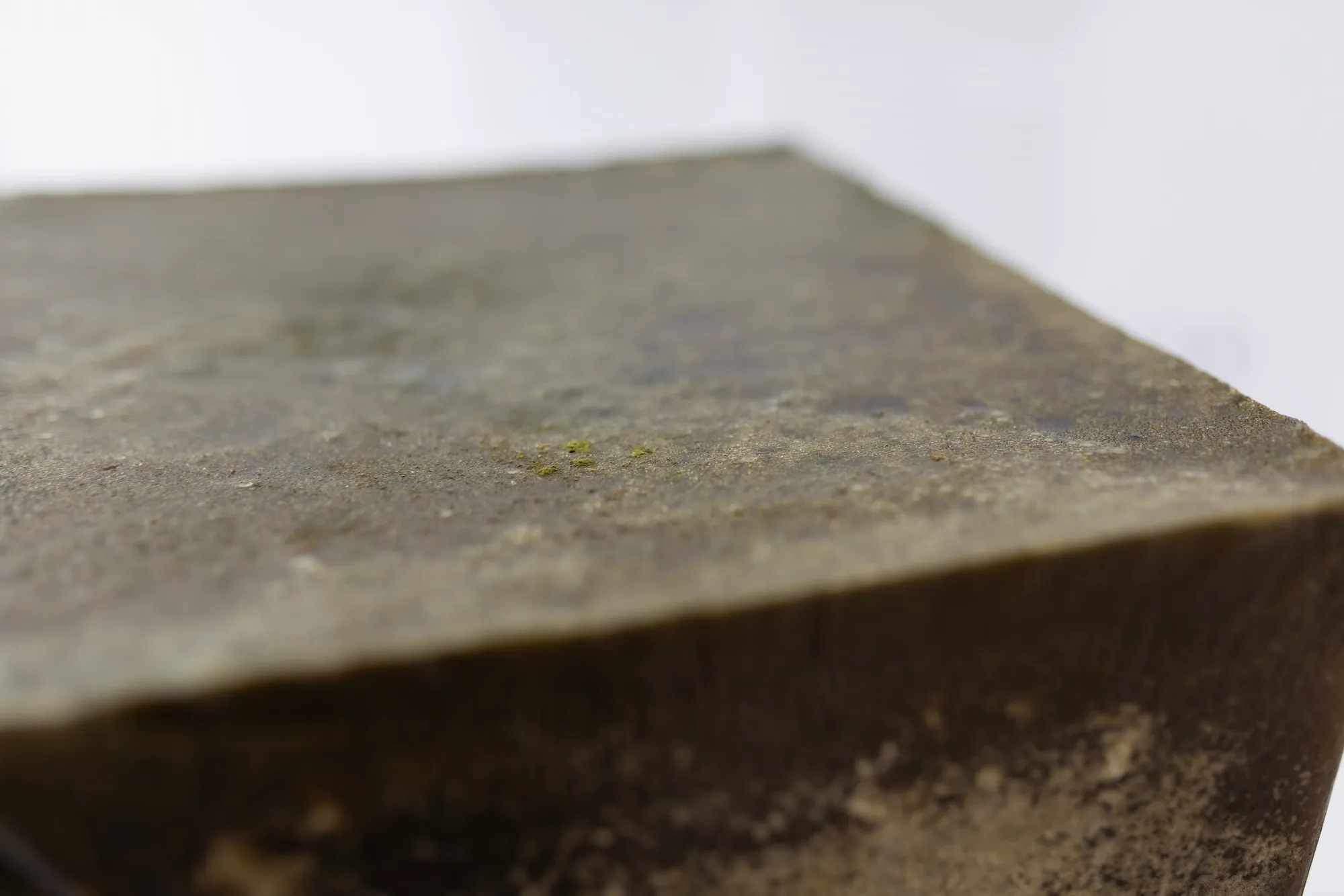 Extreme close-up of the sculpture's weathered surface, with a small speck of green moss.