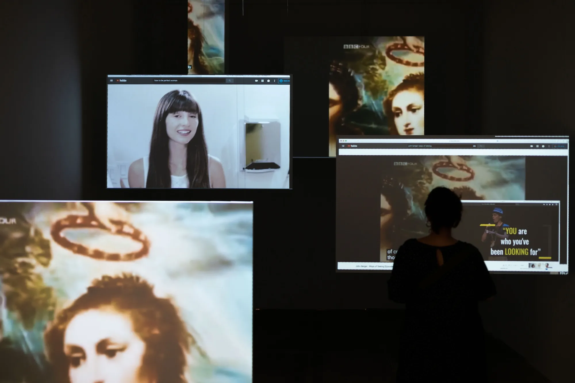 Installation view: screens showing a woman speaking to camera, a Renaissance painting, and text reading 'YOU are who you've been looking for' from a BBC adaptation of Ways of Seeing.