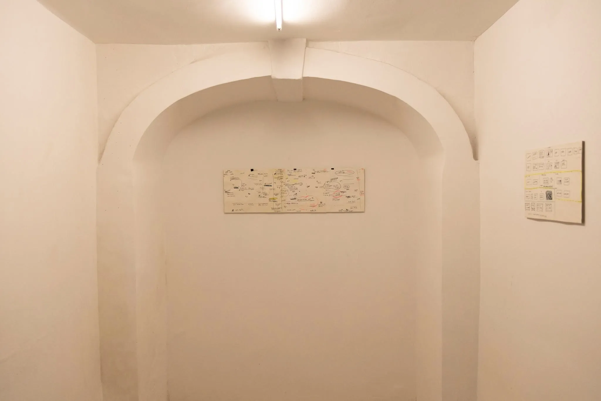 A white vaulted archway with small framed storyboard sketches mounted on the walls.