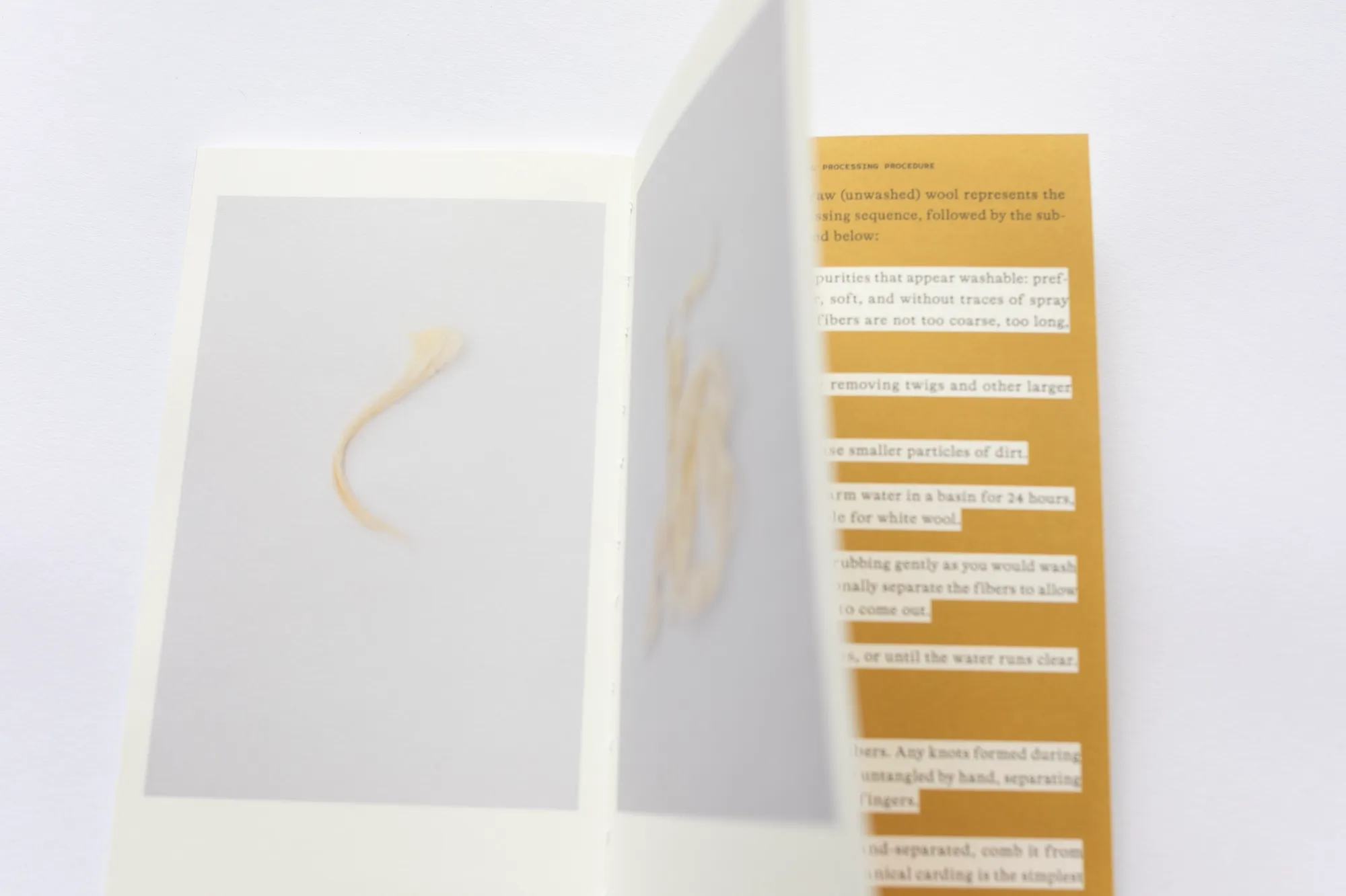 An open spread of the book showing a photograph of a wisp of raw wool beside text describing the wool processing procedure.