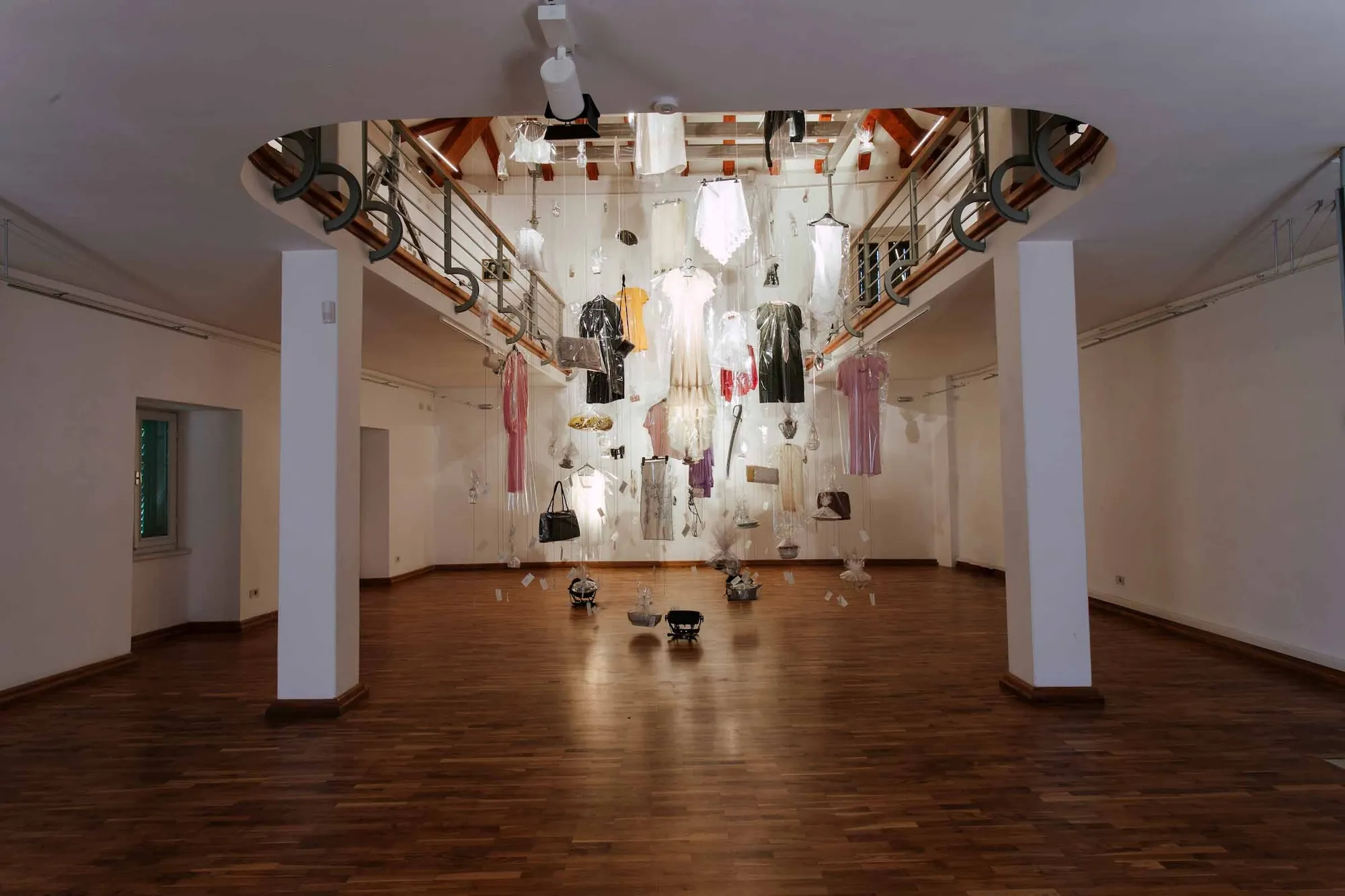 Installation view from below of objects wrapped in clear film hanging from the gallery's second floor.