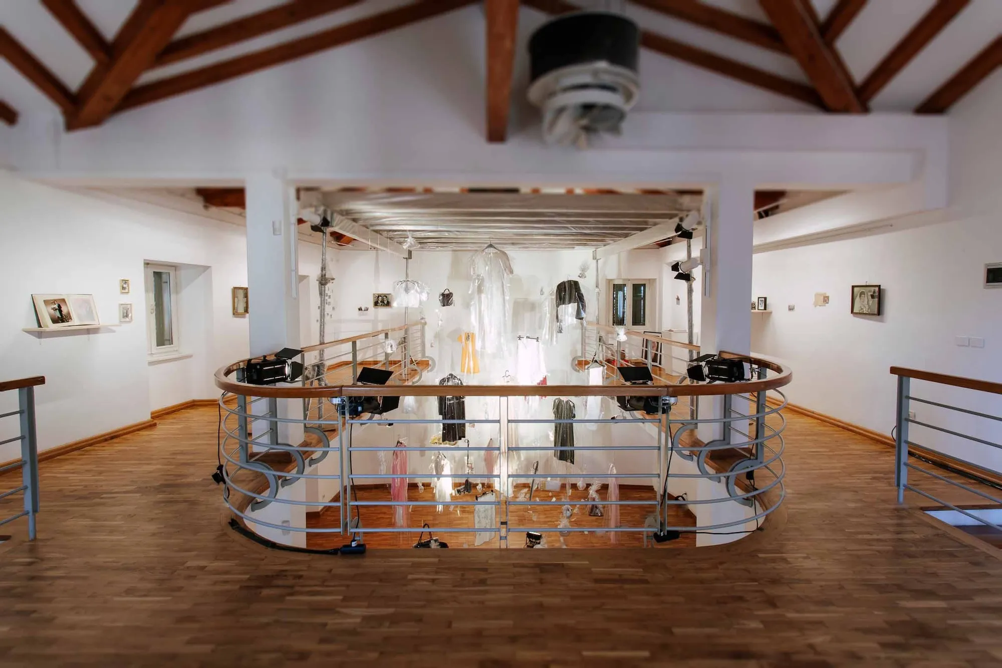 Installation view from the second-floor balcony, looking across the gallery with framed photographs on the surrounding walls.