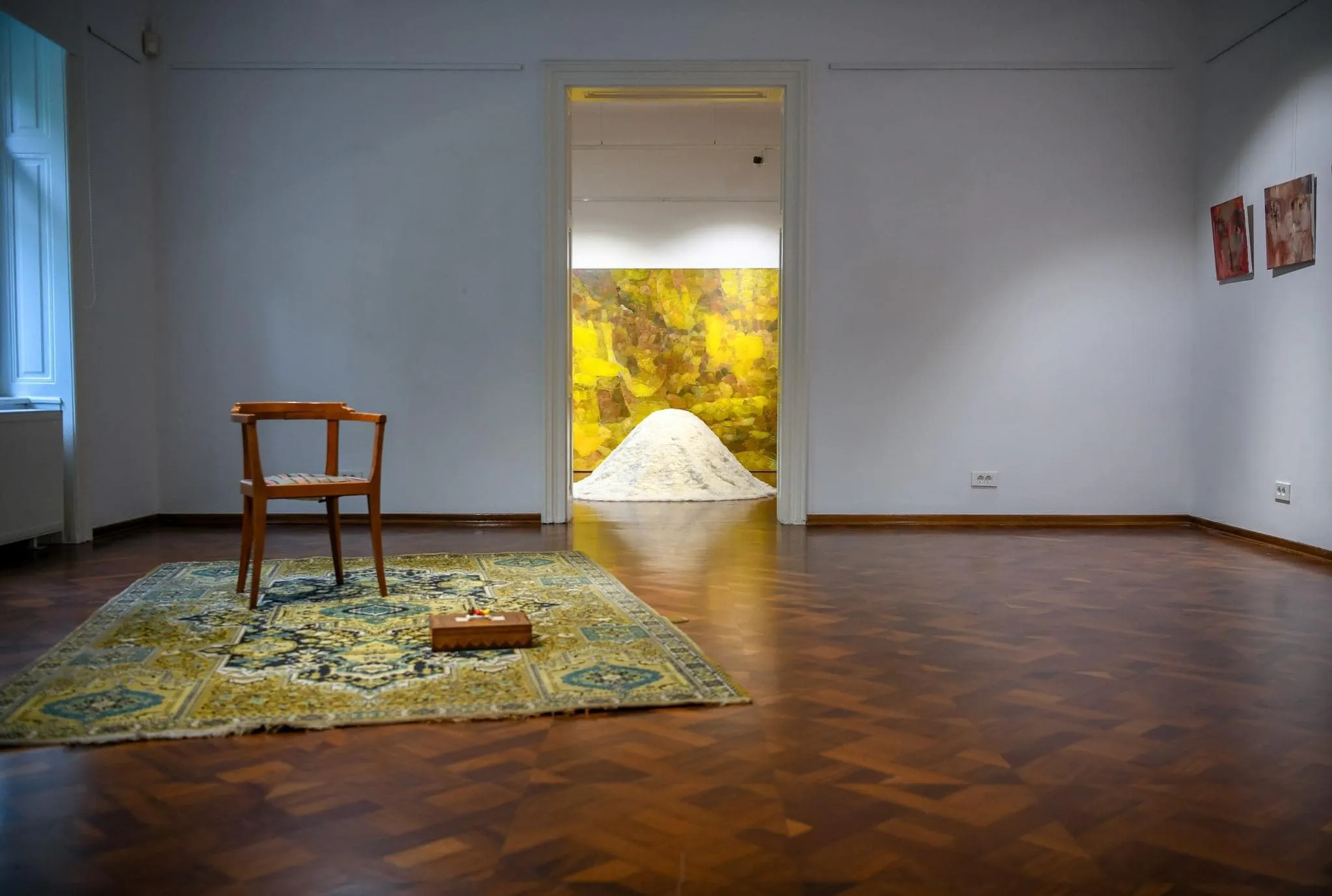 A mound of white felted wool in the corner of a dimly lit gallery room.